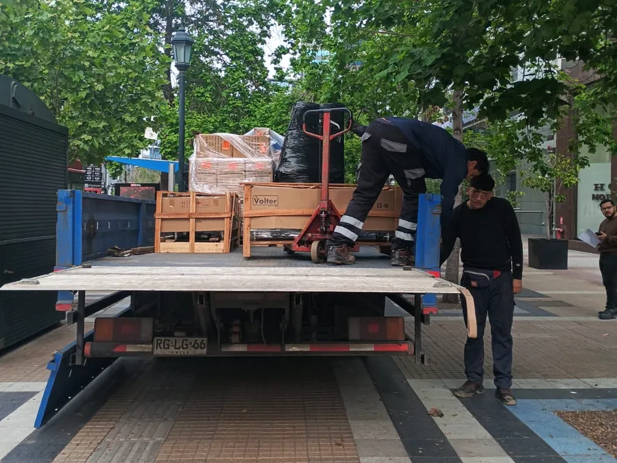 Camión de 10 toneladas con plataforma hidráulica descargando con transpaleta en la ciudad