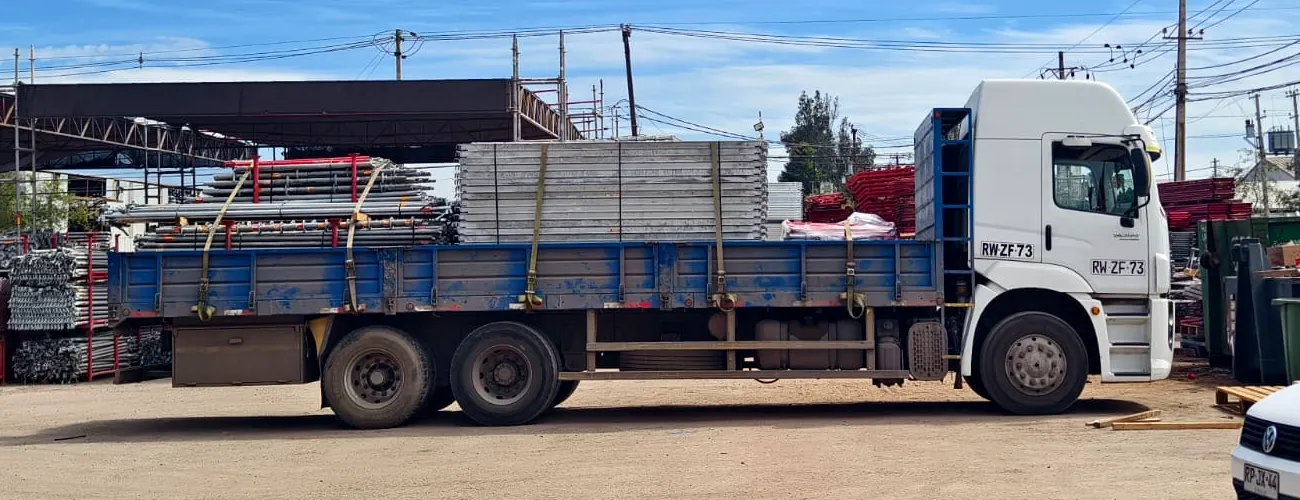 Camión de Tierras Negras con rampla cargada de andamios y paneles
